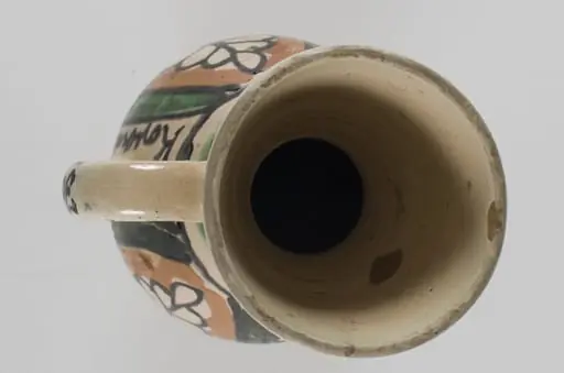 Cană cu gât lung, cu buza evazată și o toartă. Este smălțuită în interior și în exterior. Prezintă decor pe toată suprafața cu motive fitomorfe, motive florale stilizate și motive geometrice: linie, linie ondulată, punct, tablă de șah. Pe toartă scrie ”Jozsa Janos”, iar pe corp, chiar lângă toartă, scrie ”Korond 1974”. Cromatică: fond: alb; motive: bej, maro, verde, negru., by Jozsa Janos