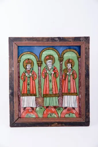 Cei Trei Sfinți Ierarhi Vasile cel Mare, Grigorie de Dumnezeu Cuvântătorul și Ioan Gură-de-Aur slujesc și săvârșesc Sfânta Liturghie împreună. Sunt înveșmântați în veșminte liturgice: sacos verde-alb-verde, felon roșu vermillon, epitrahil verde cu câte patru cruci. Sfântul Vasile cel Mare are Sfânta Evanghelie în mâna dreaptă. Sfântul Ierarh Grigorie de Dumnezeu Cuvântătorul Binecuvintează. Cei trei Sfinți Ierarhi stau cu picioarele pe perinițe rotunde de culori alternative: roșu, verde, alb. Fiecare sfânt ierarh este încadrat de două coloane și o boltă de biserică. Sunt prezente elemente arhitectură bisericească. Fondul registrului superior este albastru. Cromatica este luminoasă și armonioasă: verde, alb, roșu vermillon, roșu, albastru, negru. Este o icoană specifică picturii de Țara Făgărașului, cu un desen fin cu conturul negru și cromatica pastelată. După stilul picturii întregii compoziții, icoane poate să aparțină lui Matei Țimforea.
