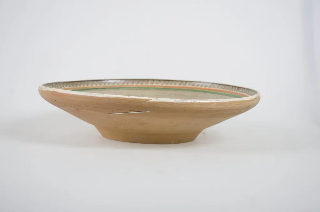 Vas ceramic de formă tronconică. Baza puțin adâncă din care pornesc pereții arcuiți spre exterior având pereții întinși și buza rotunjită. Ornament în două registre: pe fundul farfuriei o stea în opt colțuri având în fiecare vârf câte un "boboc". Delimitarea dintre bază și pereți s-a făcut printr-o porțiune jirăvită. Pereții ornamentați cu spirale și "altițe" cu linii ondulate (trei spirale și trei altițe). Marginea are o dungă jirăvită. Pe fundul vasului apare numele meșterului și localitatea "Ogrezeanu Stelian - Hurez, Valcea, Romania". Cromatică: fond: maro închis; motive: maro-roșcat, verde, alb. Smălțuit în interior., by Ogrezeanu Stelian