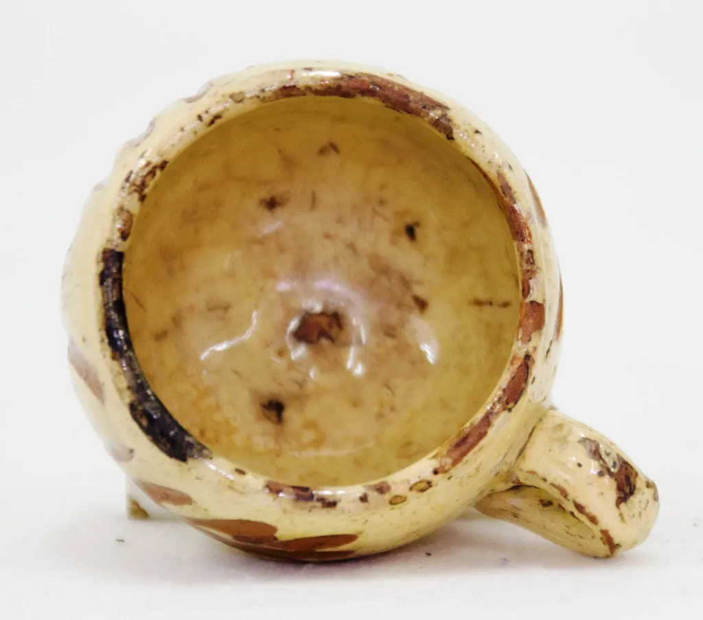 Piesa are o formă relativ cilindrică cu toartă. Are fundul îngustat și buza răsfrântă spre interior. Decorul este realizat prin incizie și pictare cu motive vegetale (crenguțe). Cromatică: galben lămâie (fondul), maro închis (decorul)., by olar