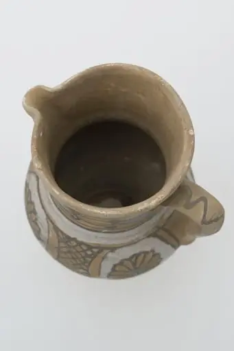 Cană de vin de formă bitronconică cu gâtul lung și buză dreaptă cu cioc. Registrele ornamentale se succed de jos în sus, delimitate de cercuri concentrice, și prezintă pe corpul vasului motive florale și geometrice sub formă de hașură întrerupte de partea de sus de o zonă cerc alb mai gros și mai apoi continuat cu cercuri concentrice ce delimitează de mijloc și de sub buză două cercuri albe groase (angoba). Cromatică: fond: alb; cărămiziu; motive: maro; gri; albastru., by Pall Antal