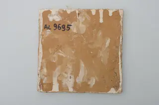 Piesă ceramică de formă pătrată, smălțuită și angobată, laturile pătratului fiind marcate de două chenare, primul vălurit, al doilea în linie dreaptă. Ornamentată cu motive zoomorfe și floral-vegetale, după fabula lui La Fontaine, Vulpea și barza: o vulpe care bea dintr-un ulcior și o barză care mânâncă dintr-un vas plat aflat pe o măsuță joasă. Pe două din colțuri, două flori completează pictura. Motivele au fost la început incizate, iar apoi pictate. Pe spate, cahla este prevăzută cu un orificiu pentru prinderea aței. Tot aici, este inscripționat numele meșterului olar, "Colibaba". Cromatică: fundal alb; motive: verde, galben, maro, cărămiziu.