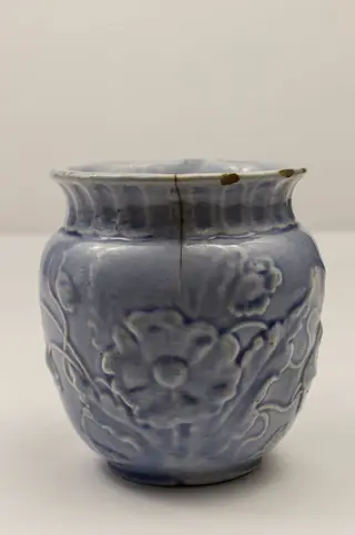 Piesă din faianță, cu aspect piriform, cu buza ușor evazată spre exterior, prevăzută cu toartă laterală semiovală. Decorul este reliefat și constă în motive florale (macul în diverse faze de dezvoltare: boboc, mac înflorit, capsule). Gâtul piesei este evidențiat printr-un brâu format din caneluri verticale. Cromatică: alb, bleu.