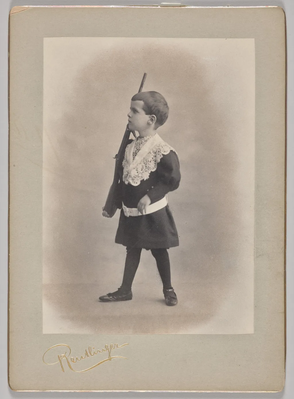 Untitled (young boy with lace collar and toy rifle), by Reutlinger Studios, 1890