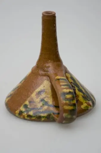 Pâlnie ceramică smălțuită, de formă tronconică, cu gura astupată cu o suprafață de lut găurită, formând o sită. La cealaltă latură a conului pâlnia este continuată printr-un tub cilindric, care se folosește la scurgerea lichidelor. Piesa de uz casnic este dotată cu un mâner care pleacă de la buză până la tubul cilindric de scurgere. Pe suprafața obiectului apar motive geometrice realizate cu pensula. Cromatică: fond: maro; motive: galben; verde., by Șchiopu Dumitru