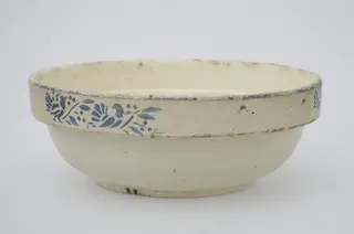 Strachină de lut de formă tronconică, cu buza ușor evazată, smălțuită în interior și la exterior. Decorată cu motive liniare, vegetale, florale și avimorfe (porumbel și porumbiță) motivele avimorfe se regăsesc pe exterior în trei registre, iar pe interior într-o casetă. Cromatică: fond: alb-bej: motive: albastru., 1850