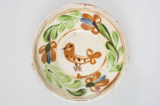 Blid de formă tronconică cu buza înaltă, smălțuit pe interior. Acesta este ornamentat cu motive florale, avimorfe, liniare și curbilinii, realizate prin pictare cu pensula. Pe buza interioară a vasului se identifică motivul geometric al liniei vălurite succedat de motive curbilinii care încadrează un registru floral-vegetal continuu dispus pe zona mediană a vasului. De asemenea, se identifică un motiv avimorf pictat pe fundul vasului și încadrat de un cerc. Obiectul este smălțuit la exterior doar pe buză, pe exteriorul buzei fiind incizate două linii. Fundul este inelar, prevăzut cu două orificii pentru agățare. Se identifică scurgeri insulare de smalț pe exteriorul buzei. Pe exterior se profilează, în zona diametrului maxim, un brâu continuu obținut prin lucrarea la roată. Cromatică: fond: alb (la interior); cărămiziu (exterior); motive: cărămiziu; verde; maro; albastru., by Unknown