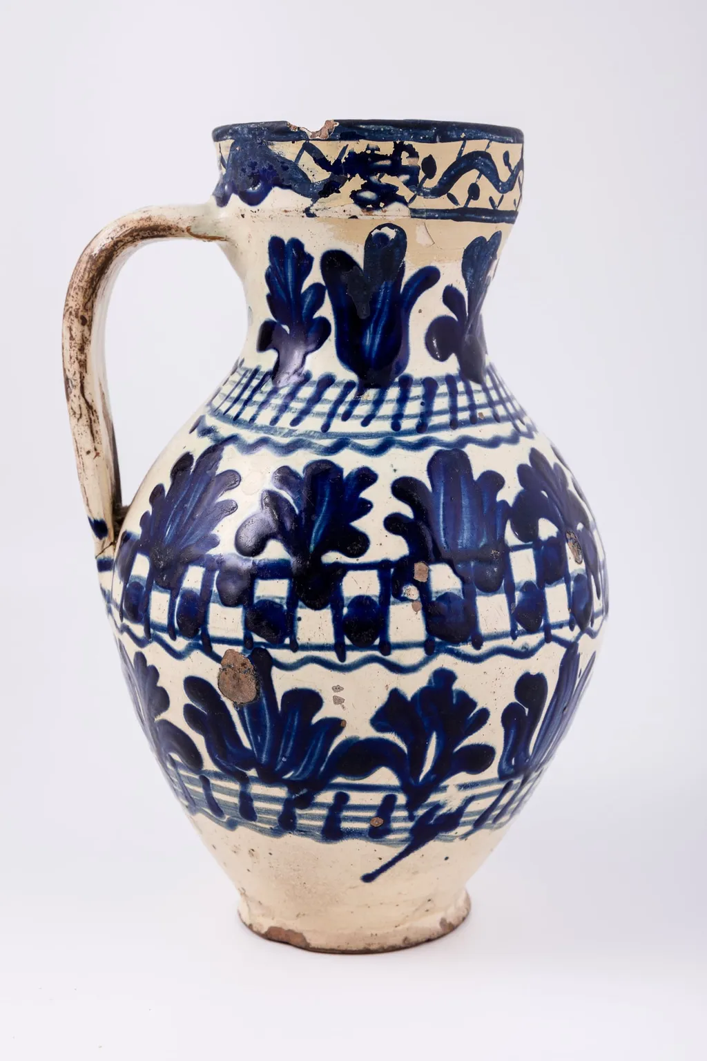 Cană piriformă prevăzută cu o toartă dreaptă și lată, gura rotundă. Suprafața decorativă a vasului este împărțită în șapte registre decorative: cel din partea superioară, pe buza vasului este dispus orizontal, iar celelalte șase, dispuse vertical. Primul registru, așezat pe marginea dreaptă a cănii redă o linie vălurită intercalată de puncte. Registrul al doilea, al patrulea și al șaselea prezintă motive fitomorfe și florale, brăduți intercalați de lalele înflorite stilizate. Registrul al treilea, dispus pe gâtul cănii și al șaptelea, dispus la bază, prezintă linii circulare orizontale intersectate de linii verticale. Registrul al patrulea prezintă tabla de șah. Toarta este pictată cu pensula. Cromatica: alb, albastru-cobalt., by Unknown, unspecified, 1850