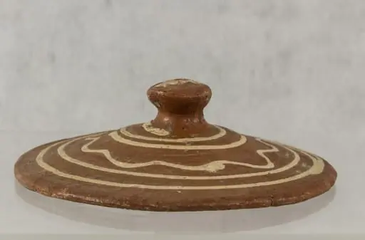 Capac cu buton, în formă de ciupercă, smălțuit pe partea exterioară. Netezire destul de bună la exterior, neglijentă la interior. Decor în trei registre, realizat prin pictare: spirală deschisă, cerc vălurit, spirală închisă. Cromatică: alb, cărămiziu., by Unknown
