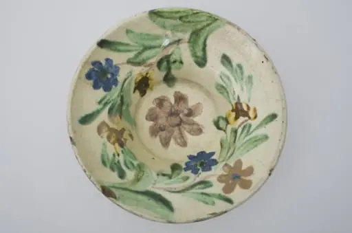 Farfurie cu marginea foarte lată și evazată, smălțuită în interior. Decor floral pe toată suprafața interioară. Cromatică: fond: alb; motive: brun; verde; galben; albastru., by Unknown