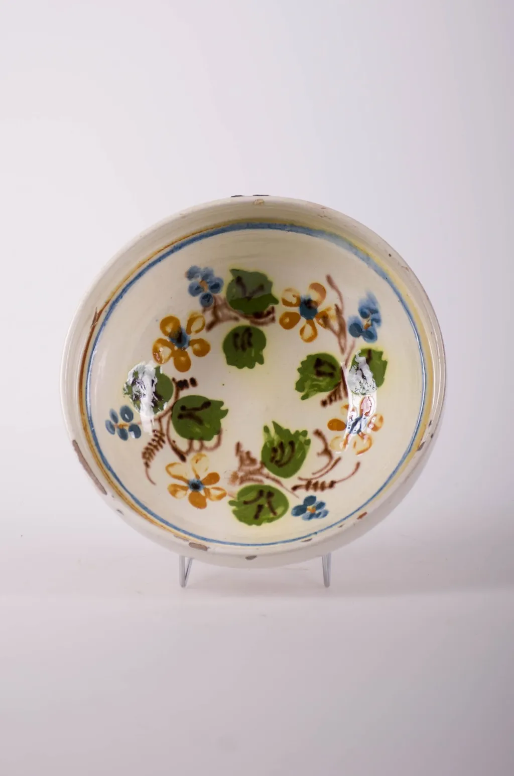 Farfurie de formă tronconică, adâncită, cu buza foarte înaltă; pe fund are găuri pentru agățare. Este smălțuit în interior și exterior (buza). Decorat cu motive geometrice: linie; motive fitomorfe; motive florale. Cromatică: fond: alb; motive: verde; maro; albastru., by Unknown, 1850