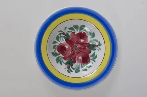 Farfurie de formă tronconică, adâncită; motive florale în centru (trandafiri); pe margine este decorat cu trei cercuri concentrice. Pe fund este o ștanță: o casă cu o pasăre pe acoperiș cu inscripție deasupra: ”MAGYAR” și dedesubt: ”1971” și un cuvânt indescifrabil. Pe fundul vasului sunt două incizii în care este introdus un șnur folosit la agățarea vasului pe perete. Vasul este smălțuit interior-exterior. Decor obținut prin pictare. Cromatică: fond: alb, motive: roșu; verde; albastru; galben., by Unknown