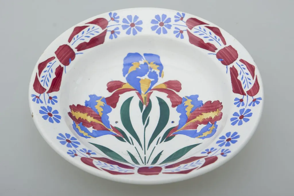 Farfurie de formă tronconică, ușor adâncită. Există două registre ornamentale, unul plasat de jur împrejurul buzei cu motive florale. Al doilea registru plasat în centru tot cu motive florale. Smălțuită. Cromatică: fond: alb; motive: albastru; verde; roșu; galben., by Unknown, unspecified, 1850
