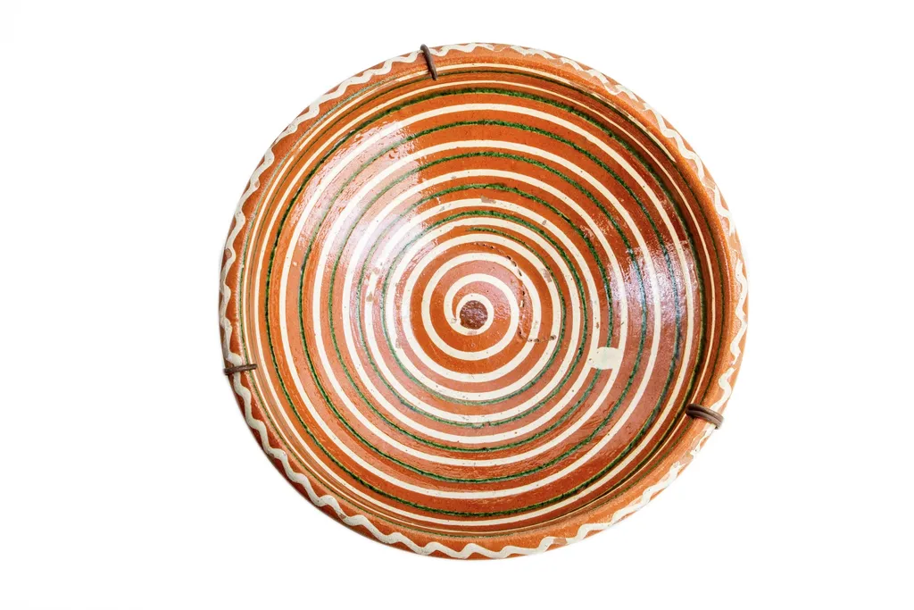 Formă tronconică; fond cărămiziu; decorul amplasat pe toată suprafața constă într-o spirală de culoare albă dublată discret de una de culoare verde. Buza vasului este decorată cu un val circular de culoare albă. Folosită la decorarea interiorului țărănesc în așa numita - cameră bună., by Unknown, 1850