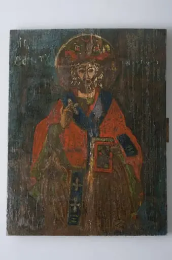 Icoana este pictată pe lemn, reprezentându-l pe Sfântul Nicolae cu veșminte arhierești (felon roșu, omofor albastru și mitră pe cap), ținând Evanghelia închisă cu mâna stângă și binecuvântând cu mâna dreaptă. Cromatică: roșu, albastru, verde, maro închis., by Unknown