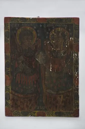 Icoană pe lemn, datată 1839, reprezentând pe Sfinții Arhangheli Mihail și Gavriil ținând în mână globul pământesc pe care sunt literele „S S S (Sfânt Sfânt Sfânt)” - cântarea îngerilor din ceruri. În registrul superior sunt scrise numele îngerilor în românește cu caractere chirilice: „Sf Arh Mihail – Sf Arh Gabriil”. Cu îmbrăcăminte ostășească, îngerii au aoreolă împrejurul capului, Mihail are sabie în mâna dreaptă iar Gavriil are crinul în mâna stângă. Icoana are un chenar realizat cu o linie subțire. Un al doilea chenar exterior cu motive florale și vegetale. Cromatică: roșu, alb, bleumarin; auriu; alb; negru., by Unknown