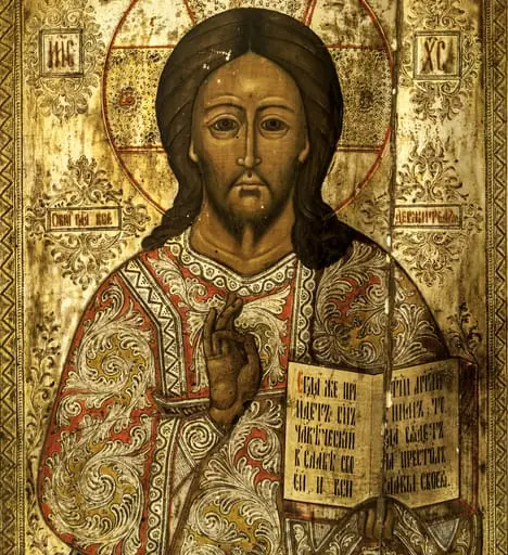 Isus Pantocrator, redat 3/4, binecuvântând cu mâna dreaptă(prin unirea degetului mare cu cel inelar), în stânga ținând cartea sfântă cu textul consacrat, în slavonă(Veniți la mine toți cei oropsiți...).această reprezentare a lui Iisus binecuvântând, cu Evanghelia deschisă, corespunde în iconografia bizantină lui Iisus Învățător, sau Hristos Ușa, icoană amplasată în stânga ușilor împărătești. Conform erminiilor, Iisus Pantocrator este redat cu Evanghelia închisă.Expresia sobră, tristă, ochii mari, părul castaniu, lung, cu cărare pe mijloc, lăsat inegal pe umeri, mustățile și barba scurte. Poartă un veșmânt cu mâneci largi cu motive florale ample, în volute(foiță argintată), interstiții umplute cu portocaliu și galben. La mâneci, klav și la gât motive geometrice în formă de zigzag și val. Aureola (nimb cruciger) depășește spațiul chenarelor, trasată cu o linie de culoare roșie, dublată pe unele porțiuni cu o altă linie de culoare albă, în interior cu motive florale și puncte incizate în stratul de foiță metalică aurită. Inscripțiile consacrate: "eu sunt alfa și omega". Dublu chenar, motive geometrice: linii, puncte și zigzaguri între două linii fin incizate pe marginea foiței, la exterior bandă vișinie cu linii albe. Inscripțiile în chenare dreptunghiulare însoțite de motive fitomorfe incizate. Cromatica: alb, galben, roșu, auriu, brun, negru, foiță metalică; Bordura o înscrie în icoanele tip Krashnuska(înroșitele)., by Unknown