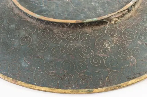 Piesă din metal pictat, incizat, de formă rotundă, puțin adâncită, cu fundul supraînălțat printr-un brâu circular. Decorul este dispus pe toată suprafața piesei, atât pe față (motive pictate: central, un buchet de crizanteme cu frunze, alături de fluturi; pe margine, un brâu circular cu motive de forma evantaiului), cât și pe spate (compoziție compactă de spirale incizate). Cromatică: albastru, verde, galben, negru, grena, roz, mov, violet, maro, alb., by Unknown, 1850