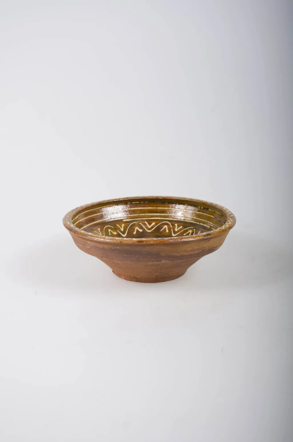 Recipient tronconic, cu gura mai largă decât baza, cu buza dreaptă și înaltă. Acesta este smălțuit doar la interior. Vasul este decorat prin pictare cu cornul, cu ornamente geometrice: spirală pe fund, linii circulare, linii vălurite și ”V”-uri înscrise pe pereți și decorații de tip val pe margine. Din punct de vedere al cromaticii, se observă un fond ocru la interior, cărămiziu la exterior, motivele fiind pictate cu alb., by Unknown, 1850