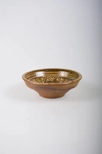 Recipient tronconic, cu gura mai largă decât baza, cu buza dreaptă și înaltă. Acesta este smălțuit doar la interior. Vasul este decorat prin pictare cu cornul, cu ornamente geometrice: spirală pe fund, linii circulare, linii vălurite și ”V”-uri înscrise pe pereți și decorații de tip val pe margine. Din punct de vedere al cromaticii, se observă un fond ocru la interior, cărămiziu la exterior, motivele fiind pictate cu alb., by Unknown