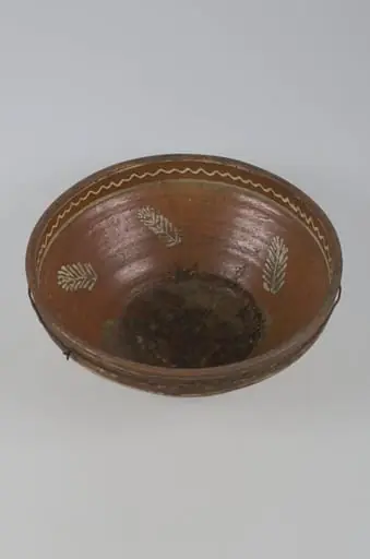 Vas adânc cu buza dreaptă, smălțuit în interior și pe exterior. Decorul este plasat pe buză (interior și exterior) format din motive geometrice: linia frântă. În interior, pereții sunt decorați cu frunze iar fundul cu frunze și flori. Cromatică: fond: brun; motive; alb; verde., by Unknown