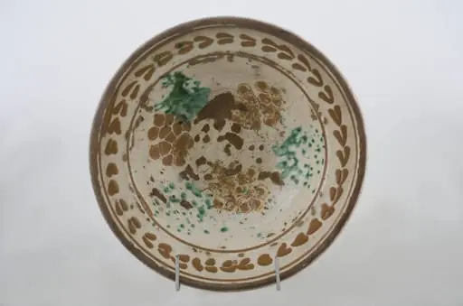 Vas ceramic de formă tronconică cu baza plată, pereții larg evazați și buza dreaptă și înălțată. După modelarea la roată, uscarea și arderea recipientului, a fost aplicat un strat de angobă în interiorul vasului, peste care a fost pictat decorul floral și vegetal stilizat, format din două registre. Primul registru, situat pe fundul și pereții vasului, și încadrat de o linie circulară, a fost decorat cu câte trei pete mari de culoare verde și galben-muștar, realizate prin stropire cu pensula. Al doilea registru, cel care decorează buza recipientului ceramic și este mărginit, la rândul lui de o linie circulară, prezintă elemente ornamentale de tipul „bobului de grâu”. Cromatică: fond: alb; motive: roșu; albastru; verde., by Unknown