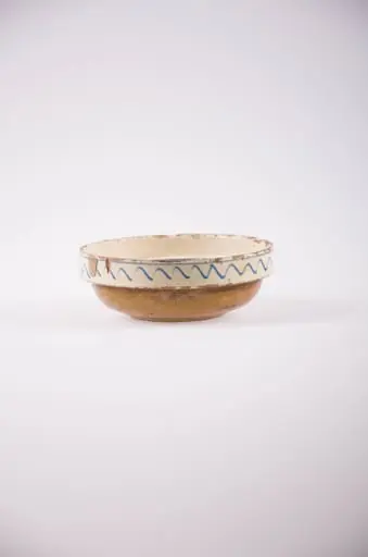 Vas de formă tronconică cu fundul ușor profilat, buza dreaptă și evazată. Smălțuit în interior și în exterior. Motiv ornamental central este floral. În exteriorul buzei avem motiv geometric în formă de val. Cromatică: fond: alb; motive: alb; verde; albastru; maro., by Unknown