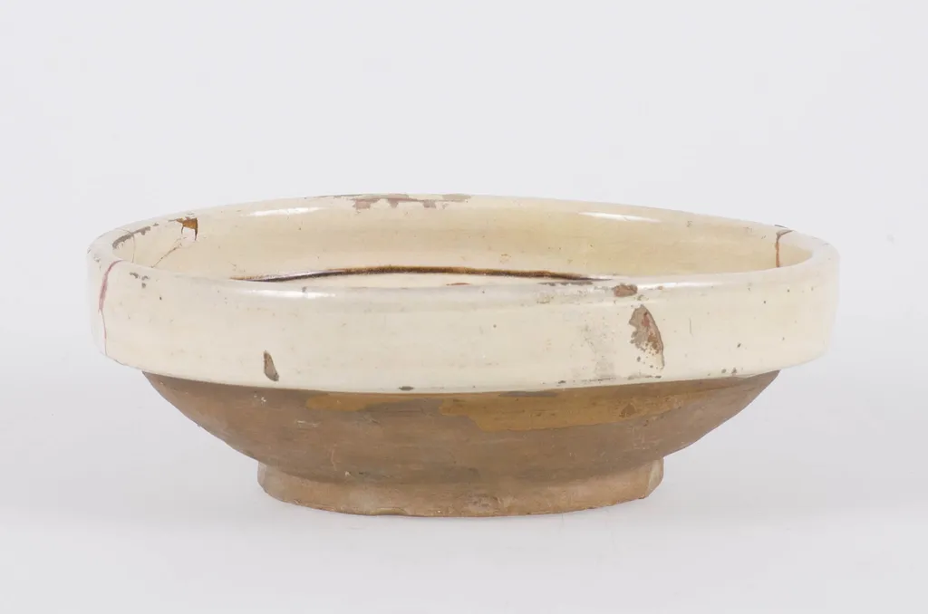 Vasul ceramic are formă tronconică, cu pereții evazați și buza dreaptă și ieșită în afară. Exteriorul pereților și fundul, au fond cărămiziu, restul suprafeței interioare și buza exterioară, având fond alb-gălbui. Decorul este format din două registre despărțite de două cercuri concentrice: unul plasat în marginea buzei și altul în centrul fundului vasului. Primul registru central este decorat cu o floare cu frunze verzi, petale maro și un punct albastru în centru. Al doilea registru amplasat pe pereții interiori ai vasului este format din două flori similare cu cea centrală mărginite spre tulpină și vârf de mai multe frunze, despărțite de două aglomerări de linii de diferite dimensiuni. Cromatică: fond: alb-gălbui; motive: verde; maro; albastru., by Unknown, unspecified, 1850