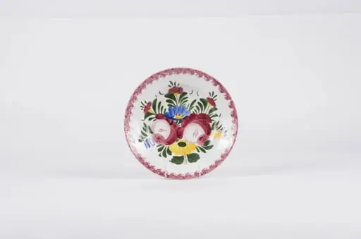 Vasul este de formă tronconică fiind smălțuit interior-exterior. Este confecționat din faianță Decorul este format din motive florale pictate pe fond alb; gura este decorată în stropi de culoare vișinie iar baza farfuriei este decorată cu motive florale. Se identifică șapte flori alcătuind motivul decorativ pe baza farfuriei. Pe spate inscripția este indescifrabilă. Cromatică: galben; albastru; verde; vișiniu; alb;, by Unknown