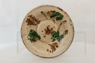 Vas de formă rotundă, adâncită, cu pereții evazați, smălțuit în interior, cu marginea ușor rotunjită, cu decor abstract realizat în tehnicile stropirii și scurgerii dirijate a colorantului maro. Cromatică: verde, maro, bej.