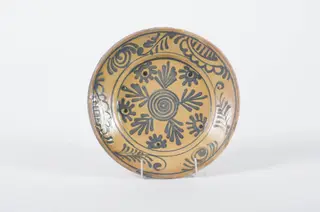 Vas de formă tronconică cu buza largă. Smălțuit în interior și buza la exterior. Decorată pe toată suprafața interioară: corpul și buza sunt delimitate de cercuri. În centrul farfuriei se întâlnețte o spirală, înconjurată de motive florale și vegetale. Cromatică: fond: ocru deschis; motive: albastru; negru., 1850