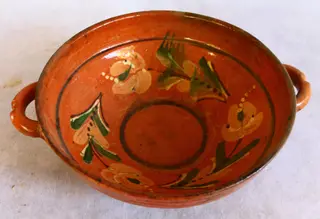 Vas de formă tronconică, cu două toarte laterale („cu urechi”) și una mică la spate. Decor geometric și floral stilizat: între două cercuri concentrice (unul pe fundul vasului, iar cel de-al doilea în partea superioară), trei flori cu frunze stilizate. Cromatică: roșu, negru, verde, alb, galben. Timp de lucru: circa două săptămâni.