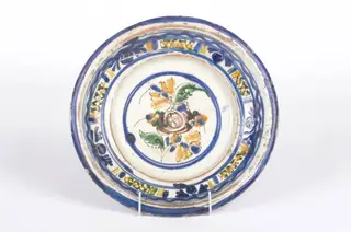 Vasul ceramic este de formă circulară, ușor adâncit, cu pereți evazați și ondulați. Decorul este amplasat pe două registre: primul registru se găsește la partea inferioară a buzei și se înscrie perimetral pe aceasta cu motive geometrice și florale (cercuri), al doilea registru este plasat central pe fundul vasului și prezintă același tip de motive. Cromatică: fond: alb-crem; motive: albastru; galben; verde; maro.